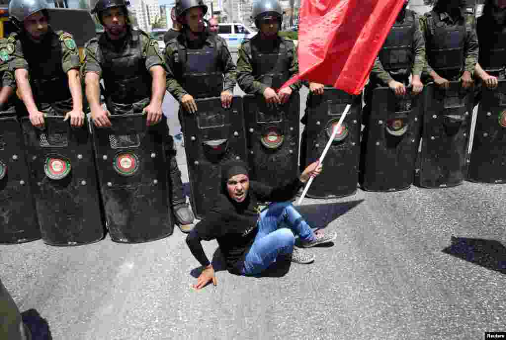 A Palestinian protester sits in front of national security force members during a protest in support of Palestinian prisoners on hunger strike in Israeli jails in the West Bank city of Ramallah.