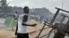 Un homme tient une machette alors que des habitants en colère brûlent des pneus et bloquent la rue pendant des manifestations qui avaient tué au moins six femmes, le 3 mars 2011 à Abobo, un quartier ouvrier de Abidjan. PHOTO AFP / ISSOUF SANOGO (Photo par ISSOUF SANOGO / AFP)