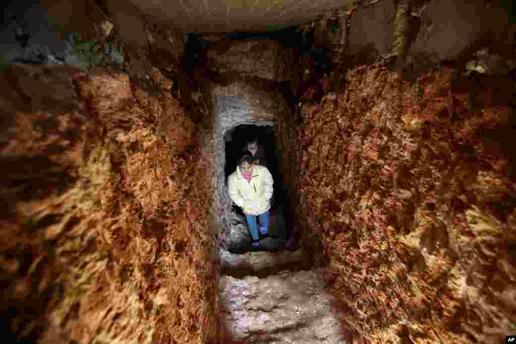 Syrian children walk out of an underground tunnel that their father made with a jackhammer for shelter from Syrian government forces shelling and airstrikes, Jirjanaz village, Idlib province, Syria, Feb. 28, 2013.