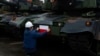 Seorang pekerja memasang bendera Polandia pada tank Black Panther K2 buatan Korea Selatan di pelabuhan Angkatan Laut Polandia, Gdynia, Polandia, 6 Desember 2022. (Foto: Michal Dyjuk/AP Photo)