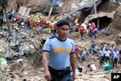 In this Sept. 18, 2018 photo, Philippine Police Senior Inspector Heherson Zambale walks at the site where victims are believed to be buried in a landslide set off by Typhoon Mangkhut as it lashed across Itogon, Benguet province, northern Philippines.