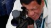 In this June 28, 2017 photo, Philippine President Rodrigo Duterte checks the scope of a Chinese-made CS/LR4A sniper rifle.