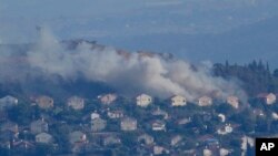 Asap mengepul dari sela-sela rumah di Kota Metula di perbatasan Israel utara yang terkena tembakan Hizbullah, terlihat dari sisi kota Marjayoun, Lebanon, Lebanon, Sabtu, 22 Juni 2024. (Foto: AP)