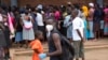 A man wearing a mask is seen near a food queue in Harare, Zimbabwe, March 25, 2020. 